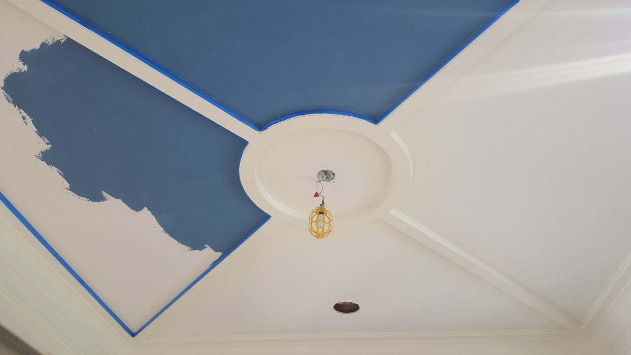 White ceiling in progress of being painted blue.