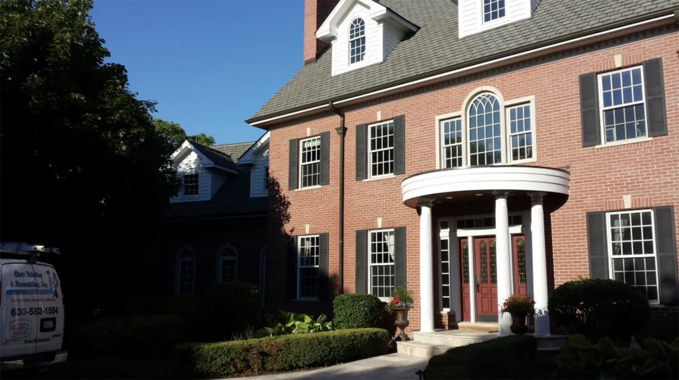 Exterior of brick house, with a chris painting and remodeling services van out front