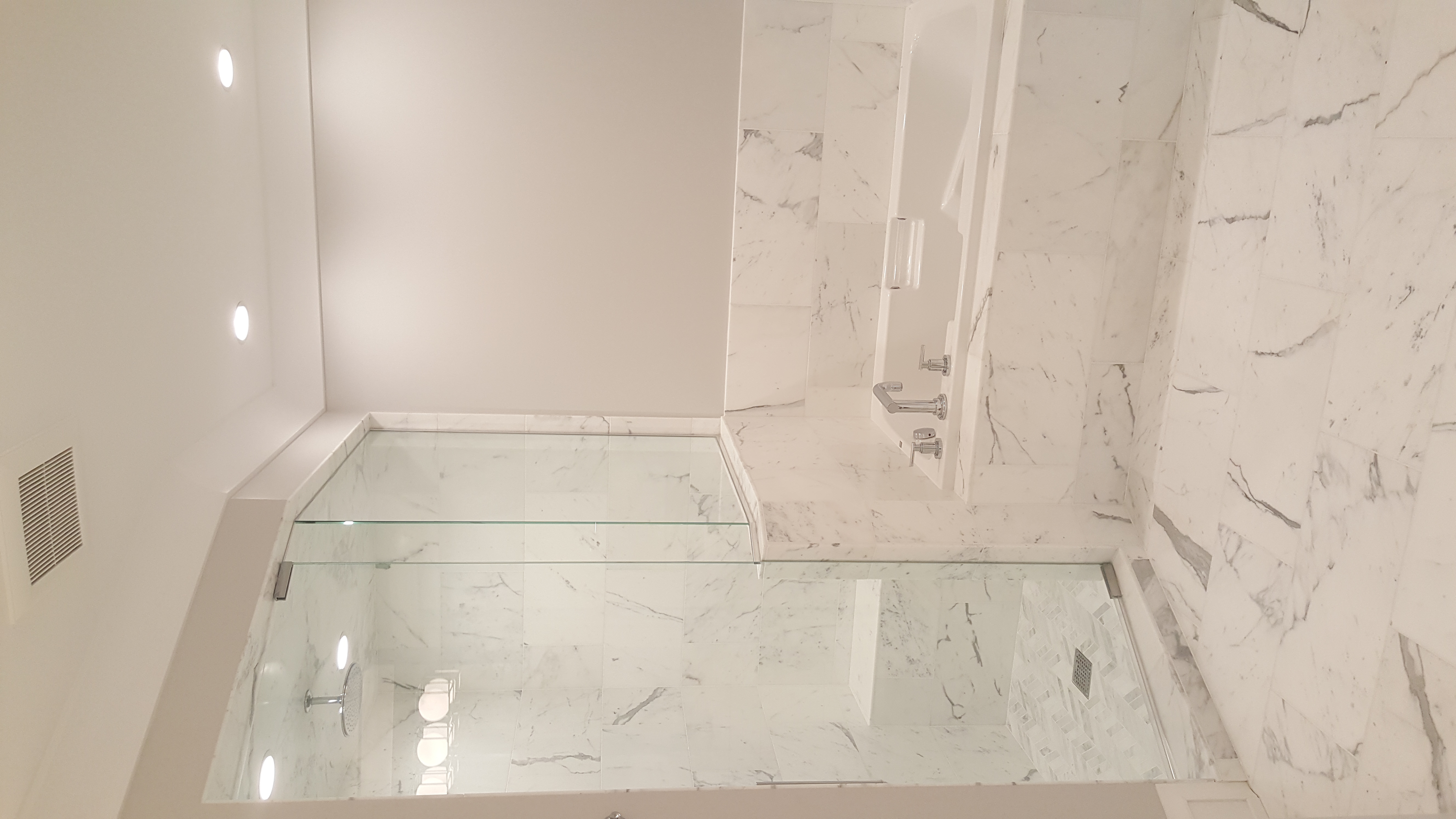 Luxury master bathroom with floor-to-ceiling white marble tile, glass-enclosed corner shower with rainfall showerhead, and marble-clad soaking tub surround by Chris Painting and Remodeling.