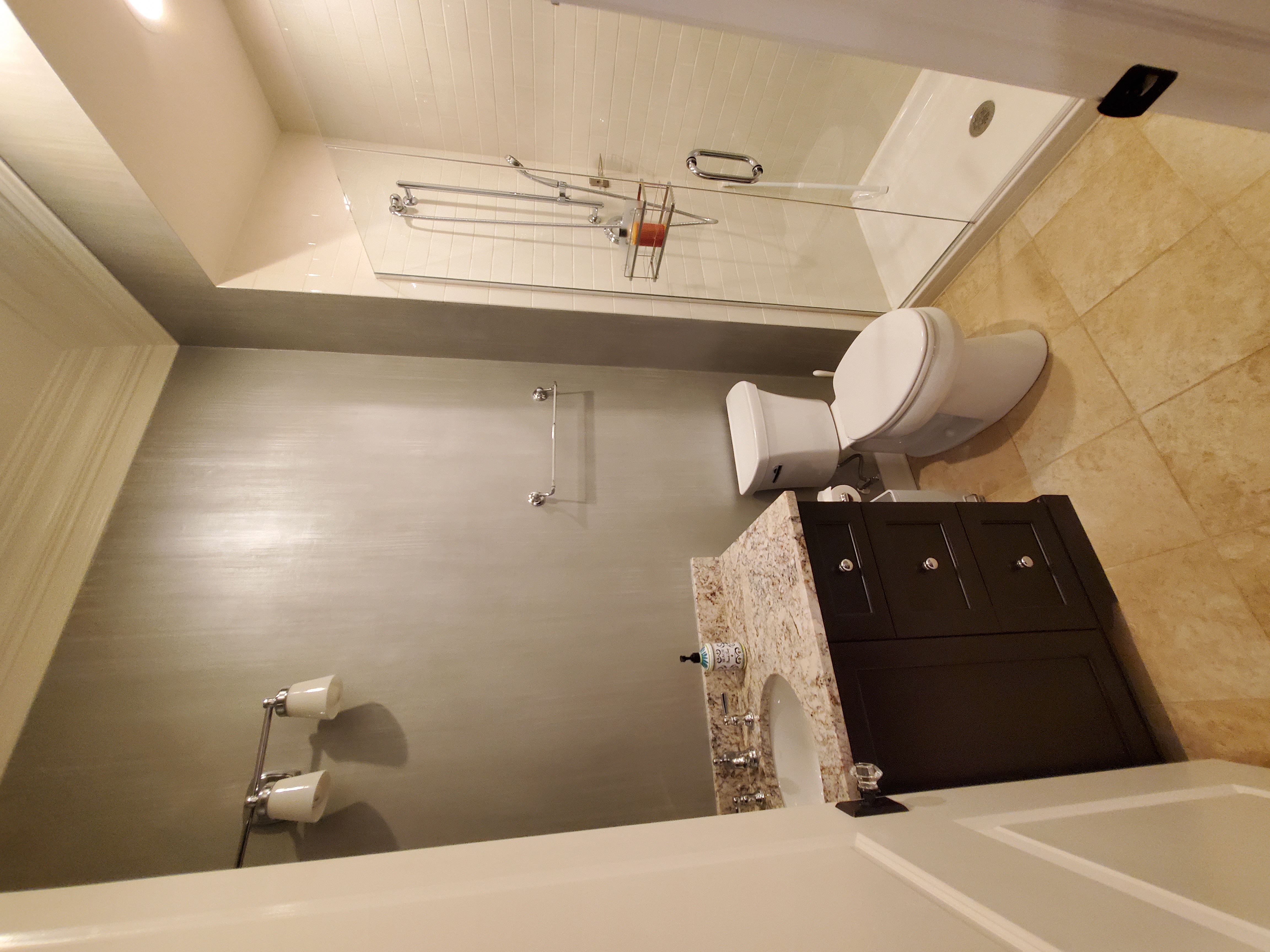 Compact bathroom remodel with dark espresso vanity, granite countertop, glass-enclosed step-in shower with white subway tile, metallic accent walls, and chrome fixtures by Chris Painting and Remodeling.