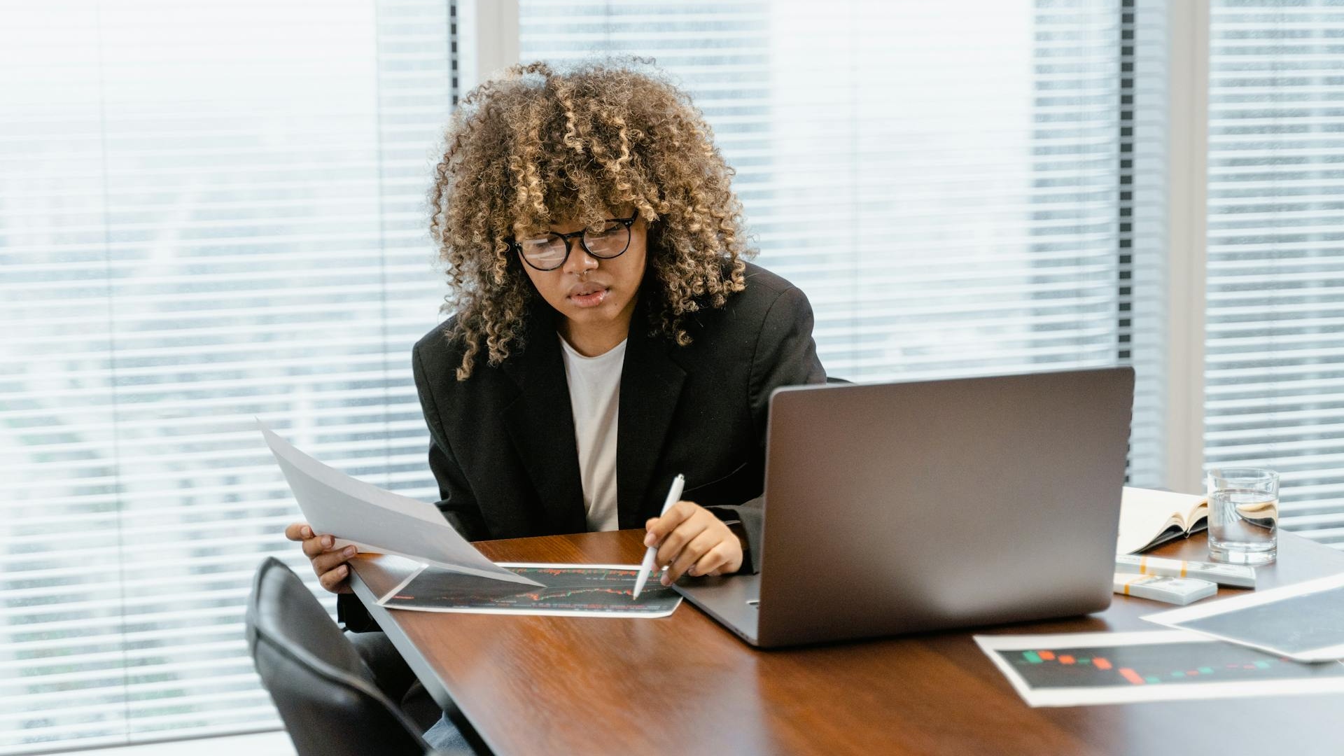 Woman in office using laptop and looking at documents