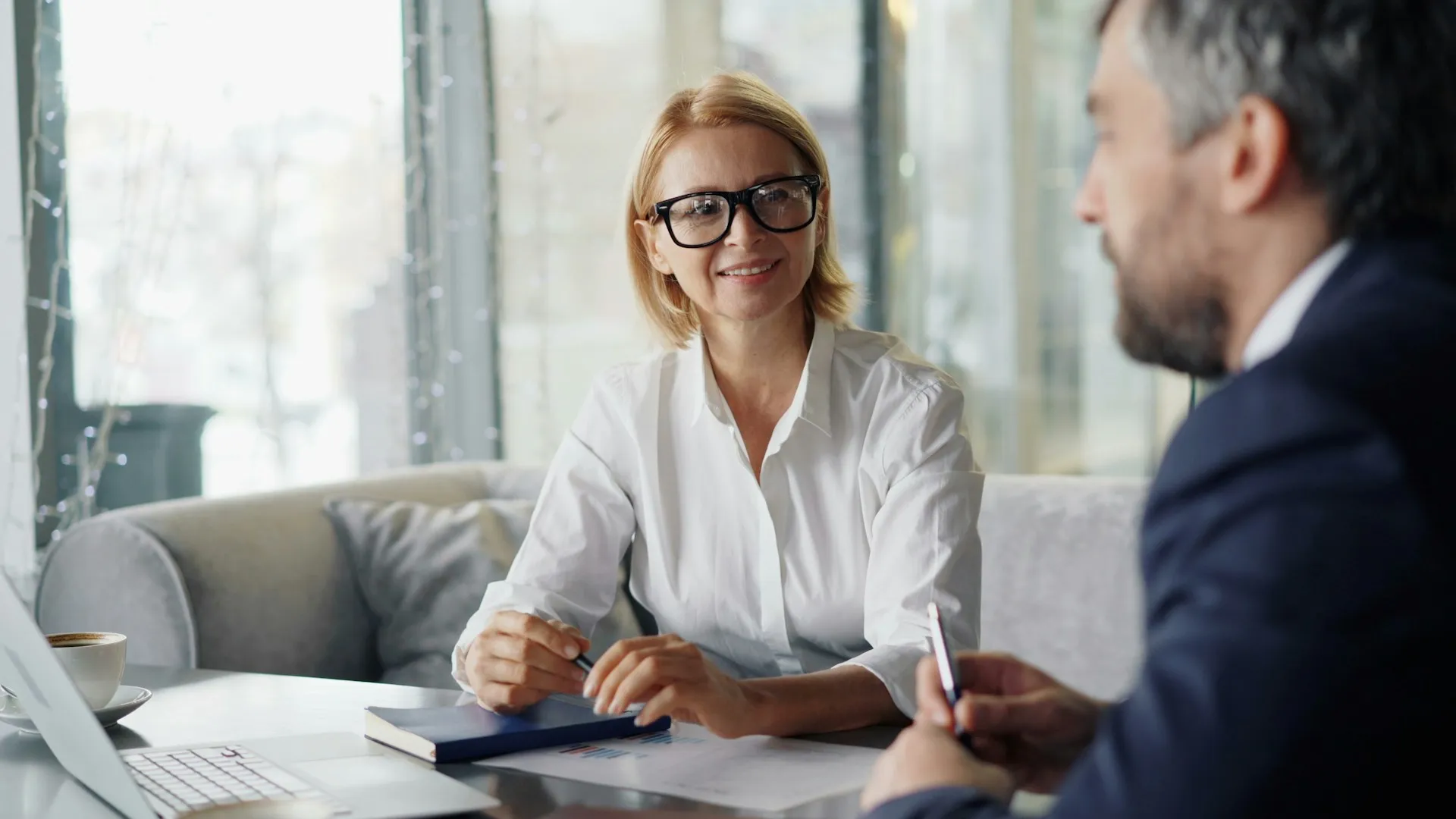 A man and a woman sitting at a table with a laptop