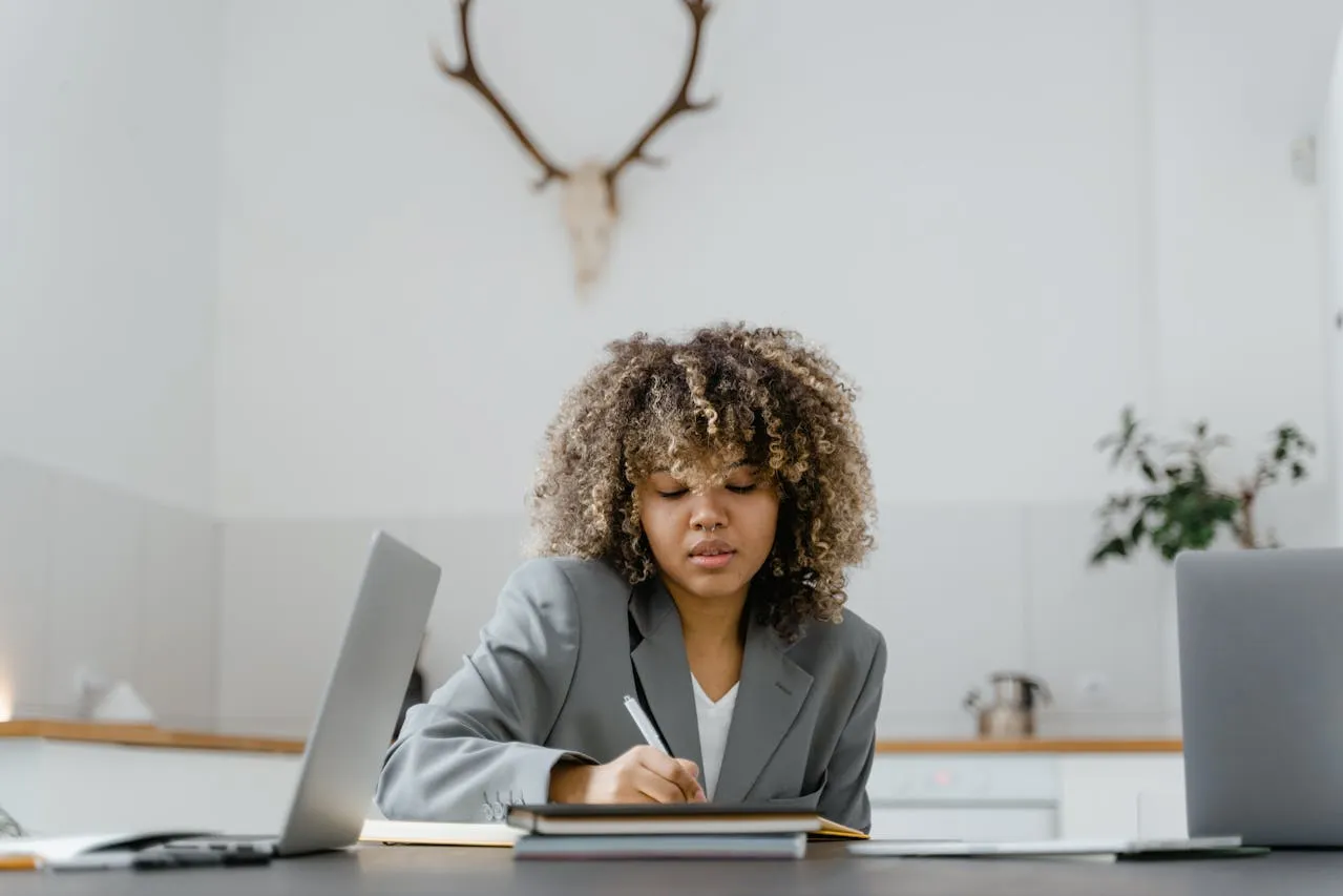 Woman in Black Blazer Writing on a Notebook