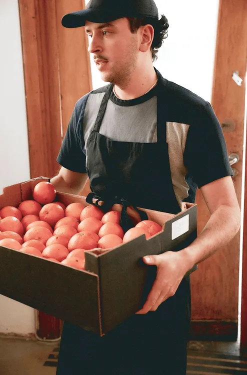 Image of a man holding a box of oranges
