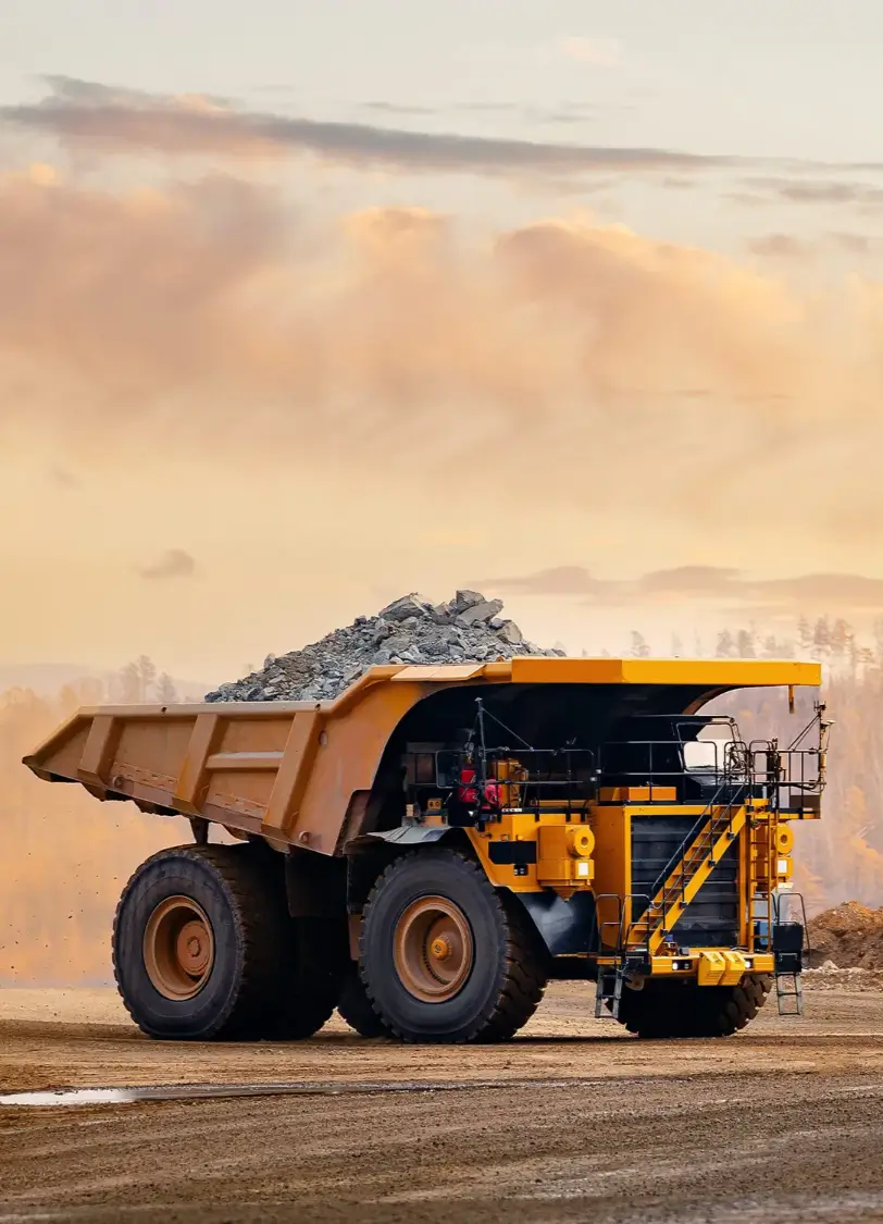 Heavy-duty dump truck loaded with rocks, set against a sunset backdrop, representing specialized trucks for construction and mining industries.