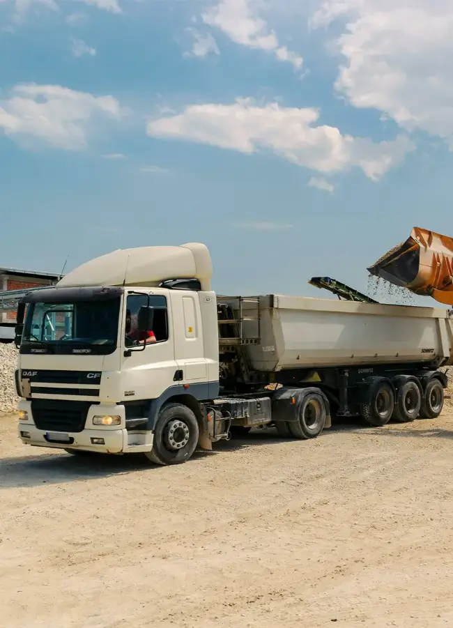 Heavy-duty dump truck loaded with rocks, set against a sunset backdrop, representing specialized trucks for construction and mining industries.