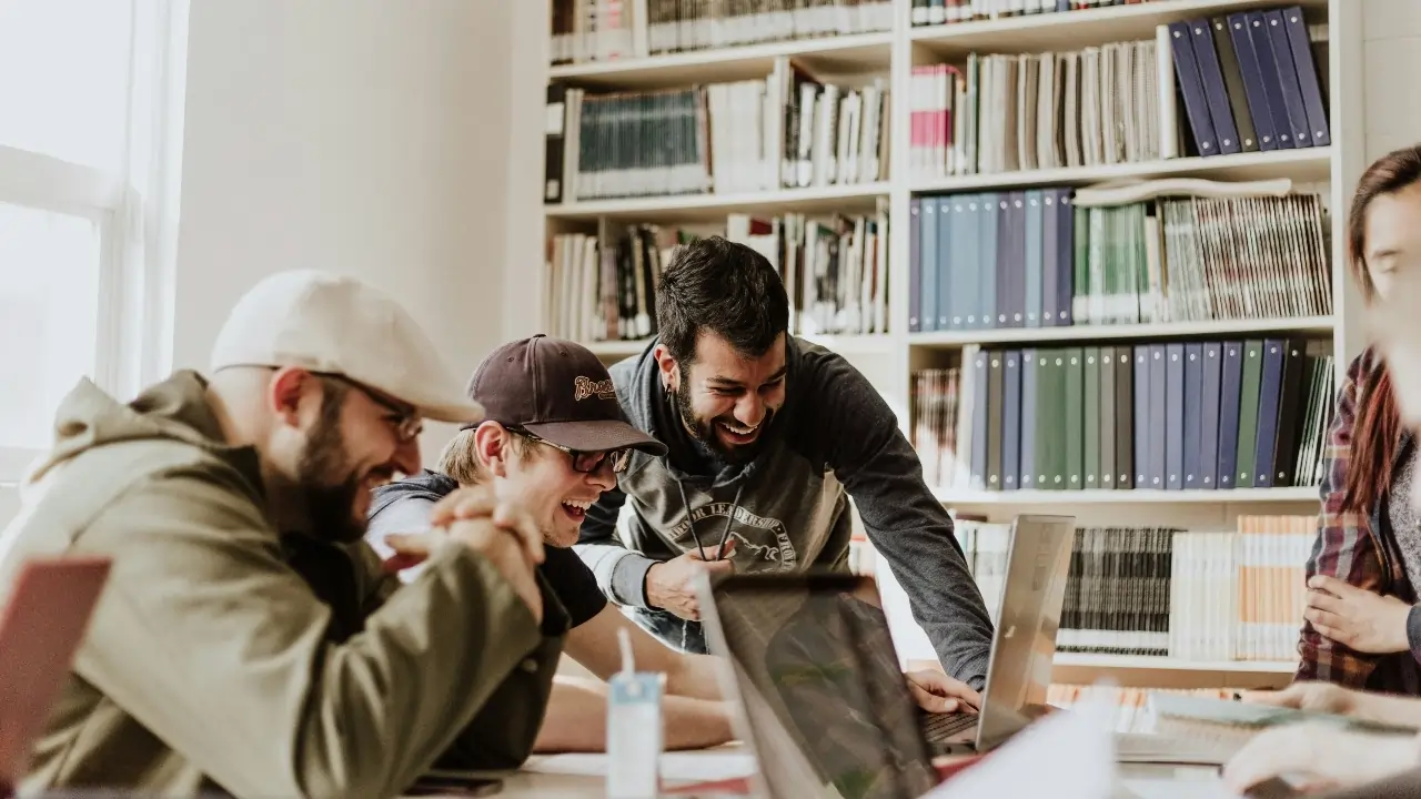 Three men laughing while looking at a laptop