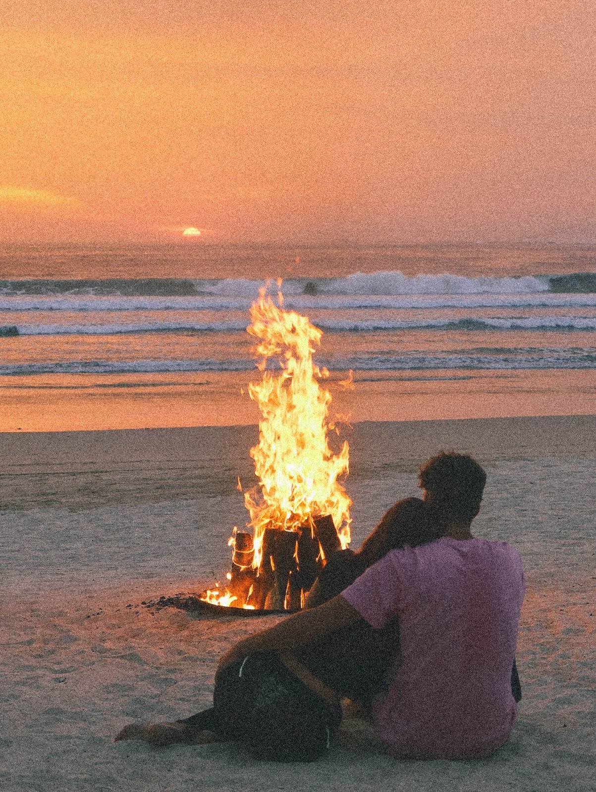 Two couples enjoying a bonfire by the beach.