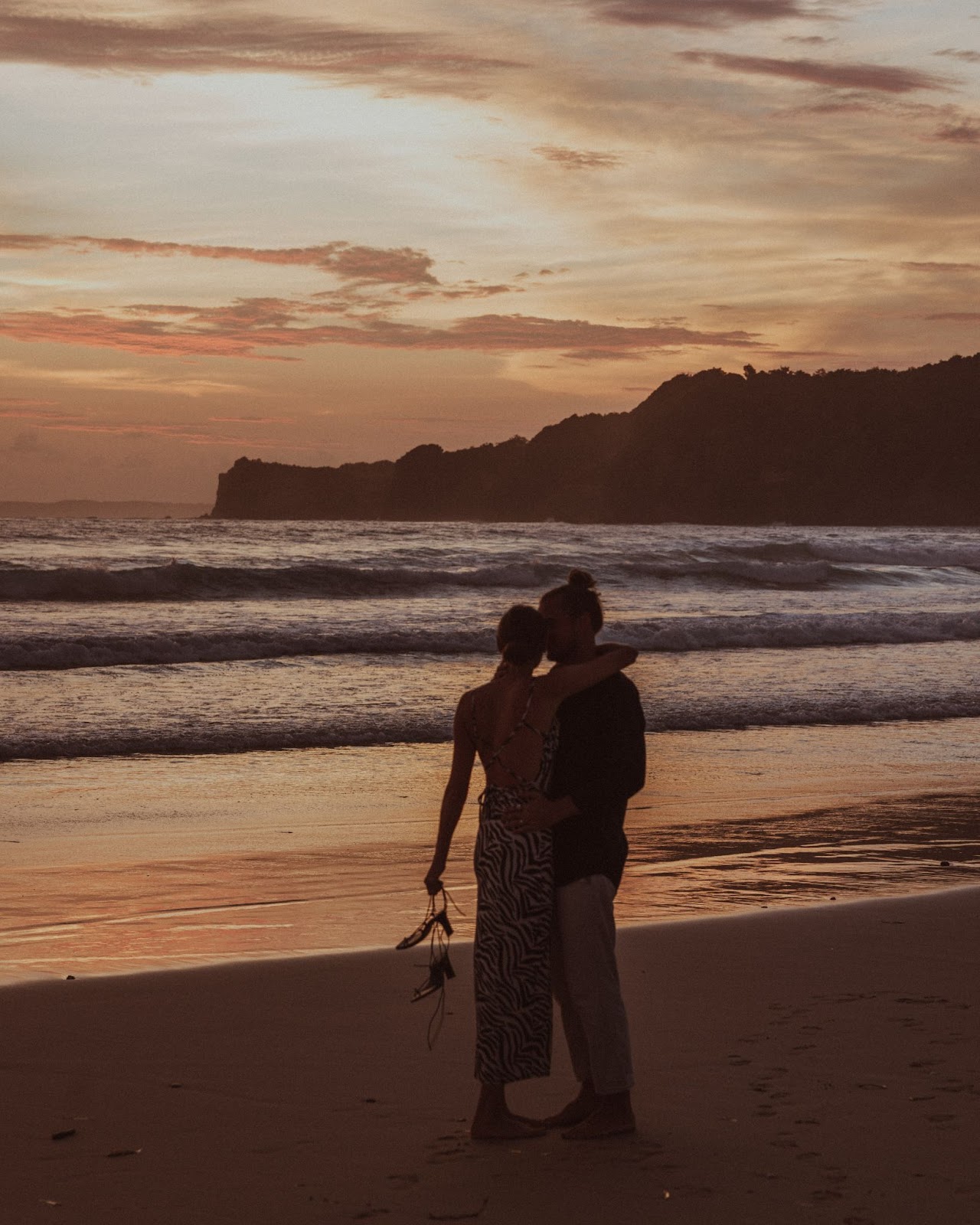 A couple cuddling by the beach while sunset