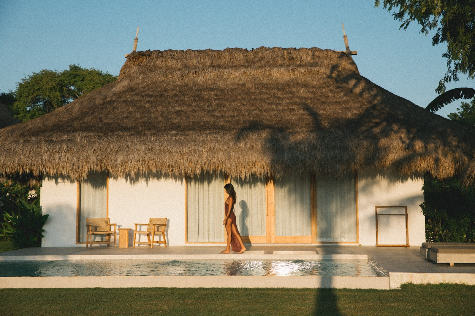 A woman walks by a pool in front of a villa at The Sanubari.