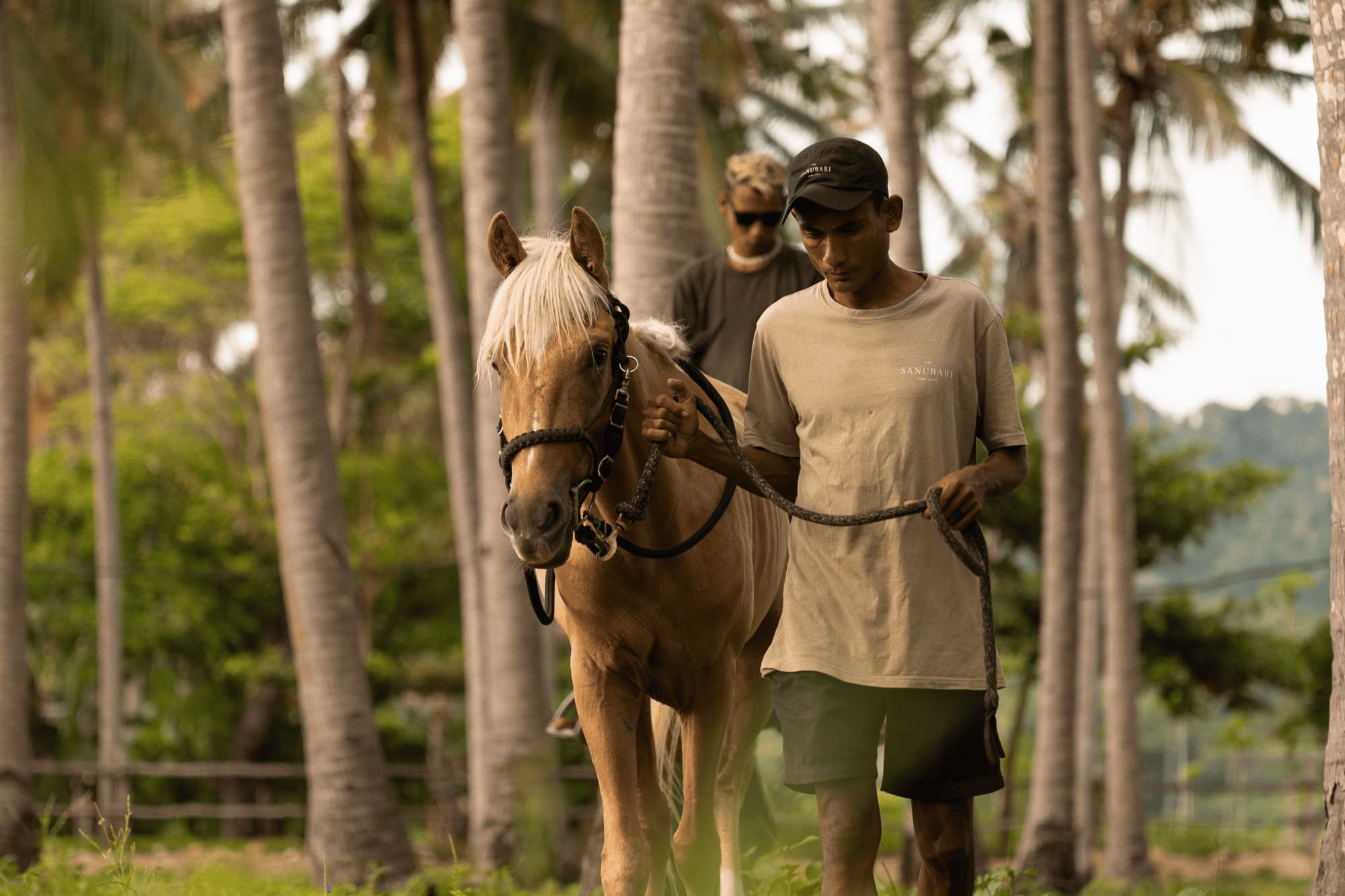 A man is riding a horse accompanied by his horse handler