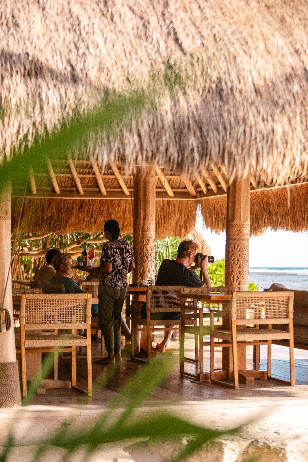 Guests dining at an open-air restaurant overlooking the beach