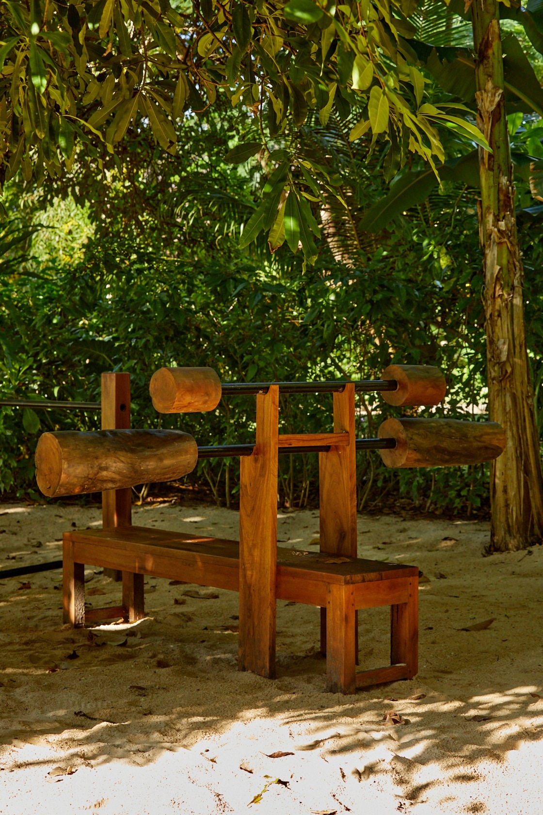 Handcrafted outdoor wooden bench press station surrounded by tropical jungle at The Sanubari Resort open-air gym, West Sumba Indonesia