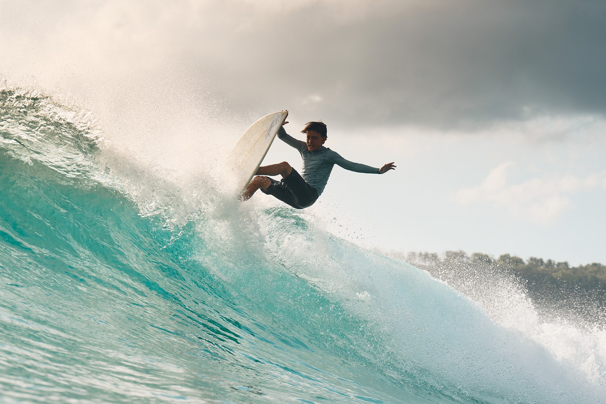 Mother and daughter bodyboarding together in the whitewash on a Sumba beach at golden hour