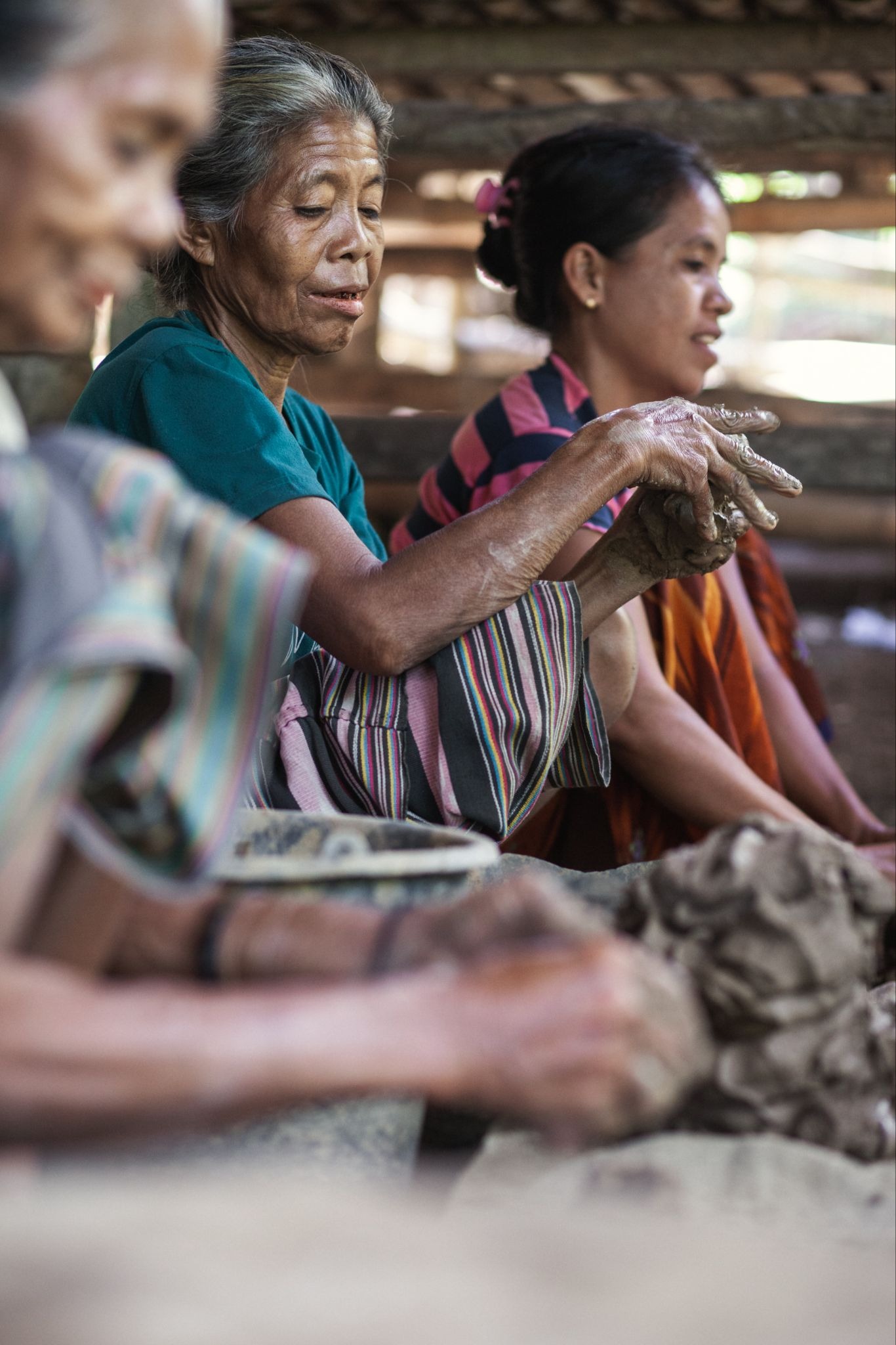 Local Sumbanese women artisans shaping raw clay by hand during a traditional pottery class in a Sumba village