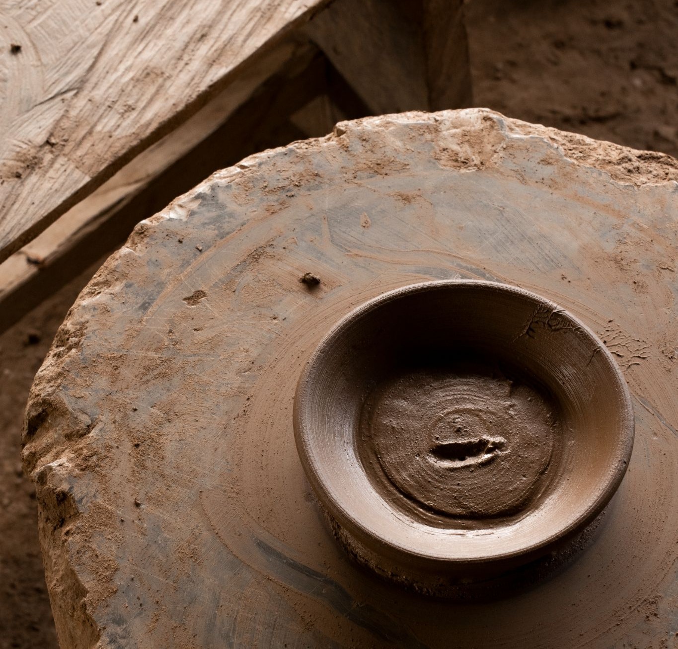 Freshly shaped clay dish resting on a traditional stone pottery wheel in a West Sumba village.