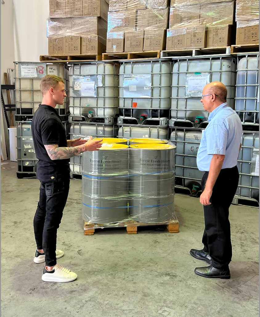 Two men in a warehouse talking to each other.