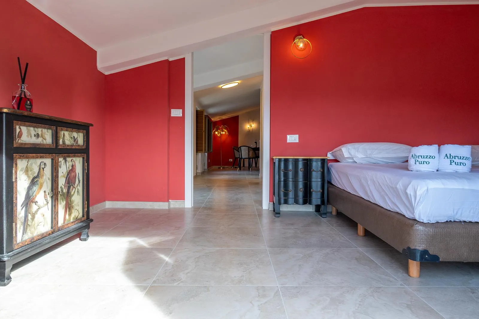 Ruime slaapkamer met warmrode muur in een appartement van Abruzzo Puro