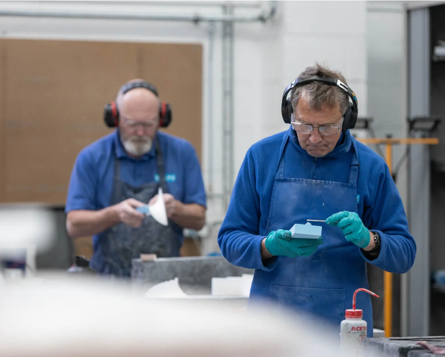 Two Shape finishers hand-working machined foam parts at the bench