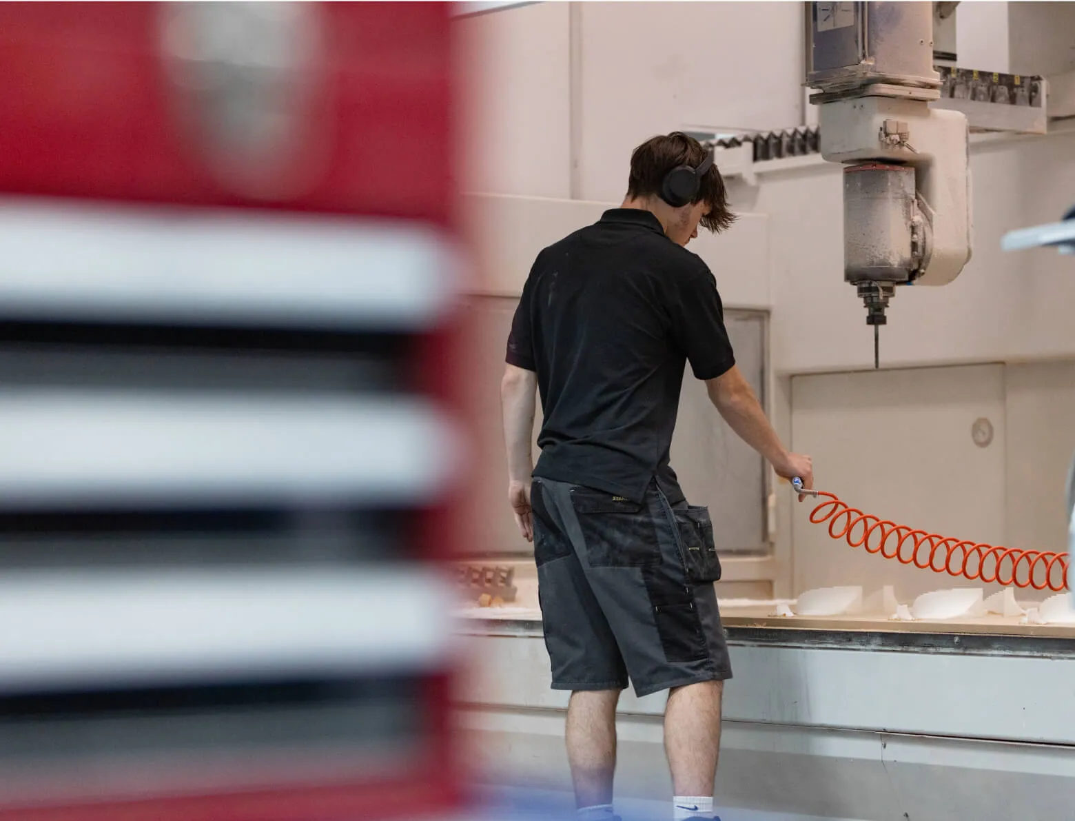 Machine operator clearing a bed of machined parts on the shop floor at Shape