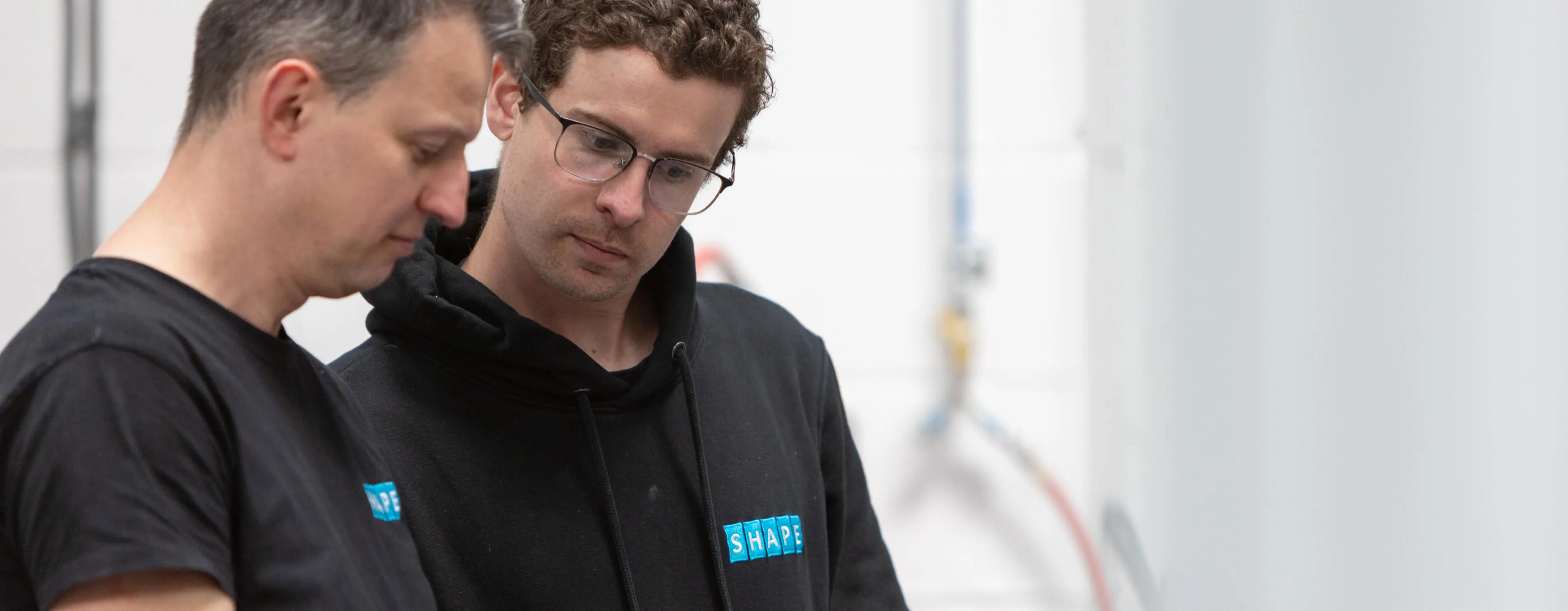 Two members of the Shape team in branded workwear on the shop floor