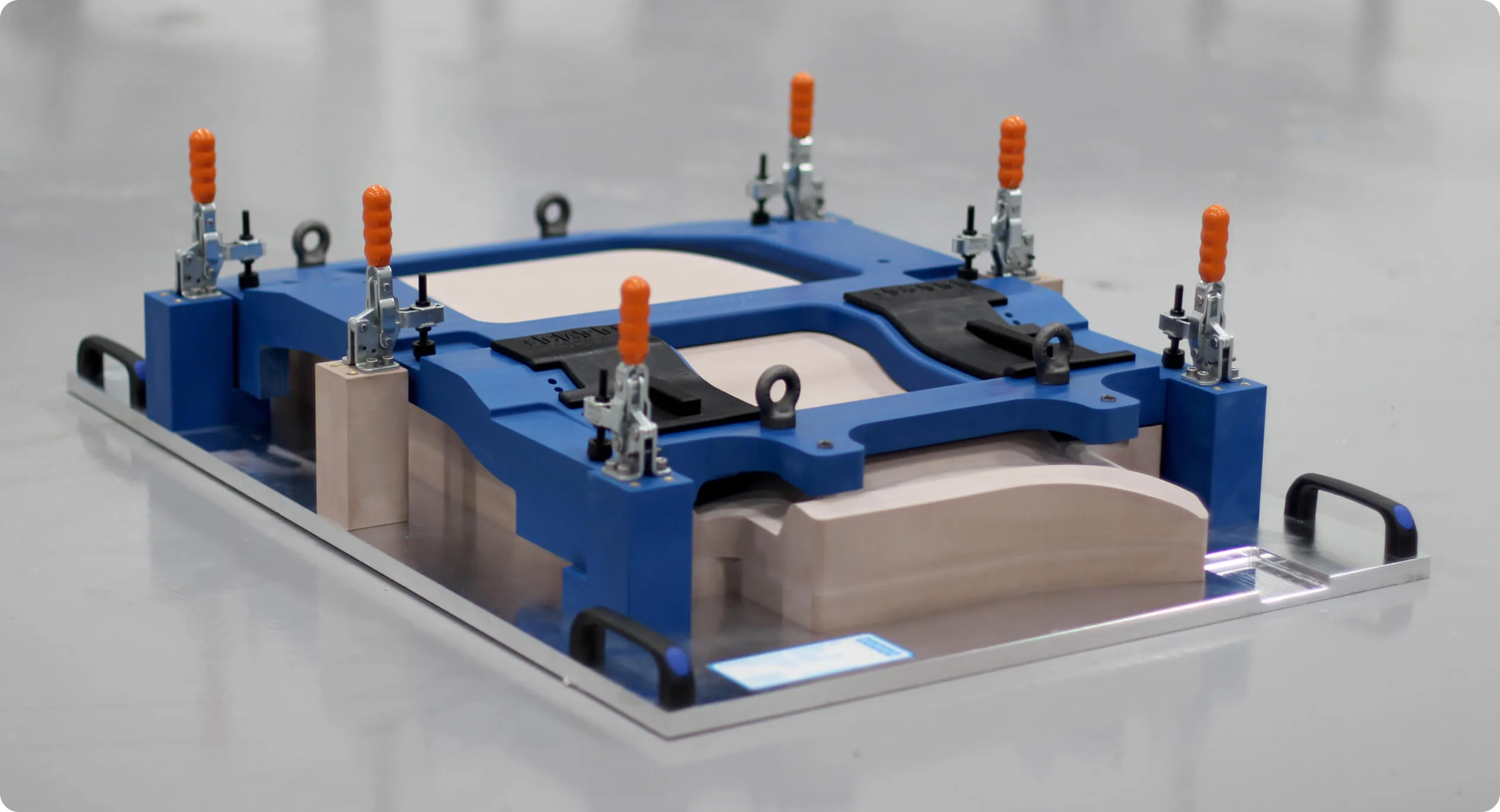 Blue machined fixture with toggle clamps holding a tooling board part