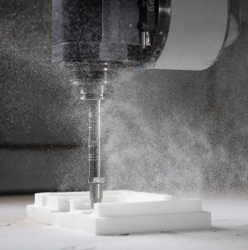 Cutter machining a white foam block on a 5-axis machine at Shape, dust thrown into the air