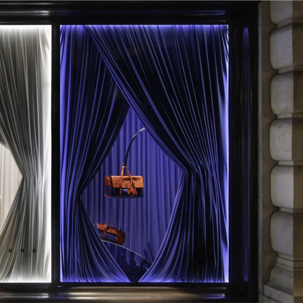 Luxury retail window display lit in blue with draped fabric