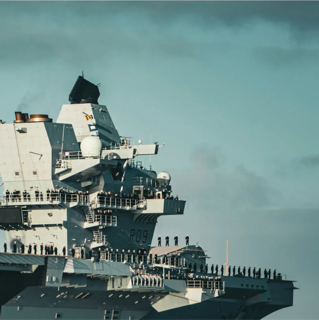 Royal Navy aircraft carrier R09 at sea with crew lining the deck