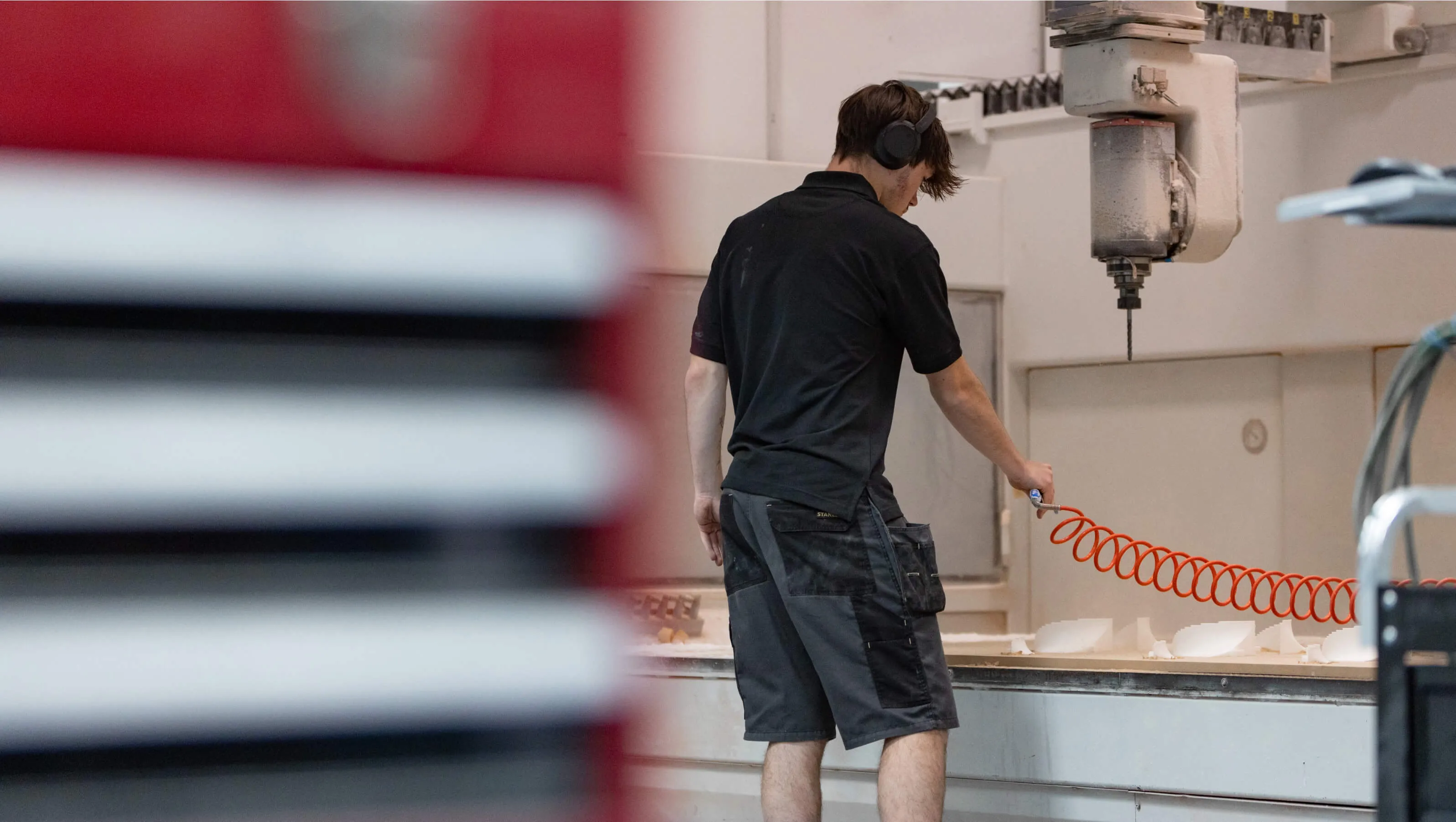 Machine operator clearing a bed of machined parts on the shop floor at Shape
