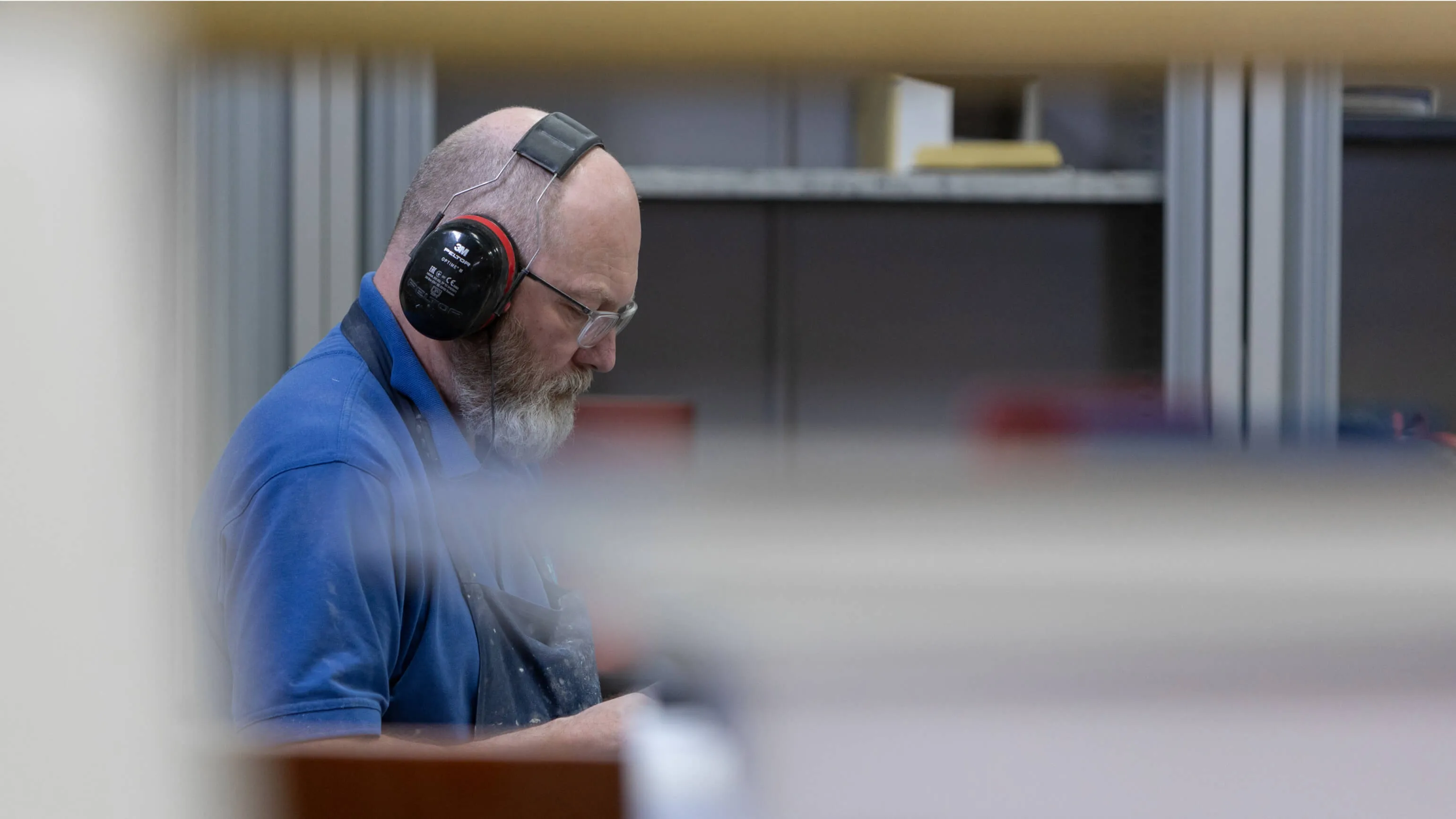 Shape machinist in ear defenders working at a machine on the shop floor