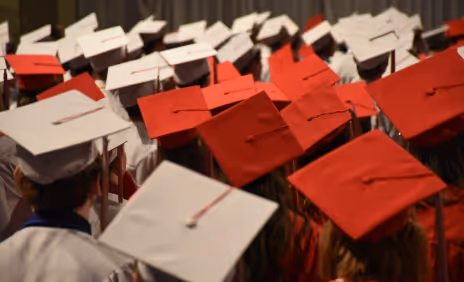 A group of graduates in red and white caps and gowns