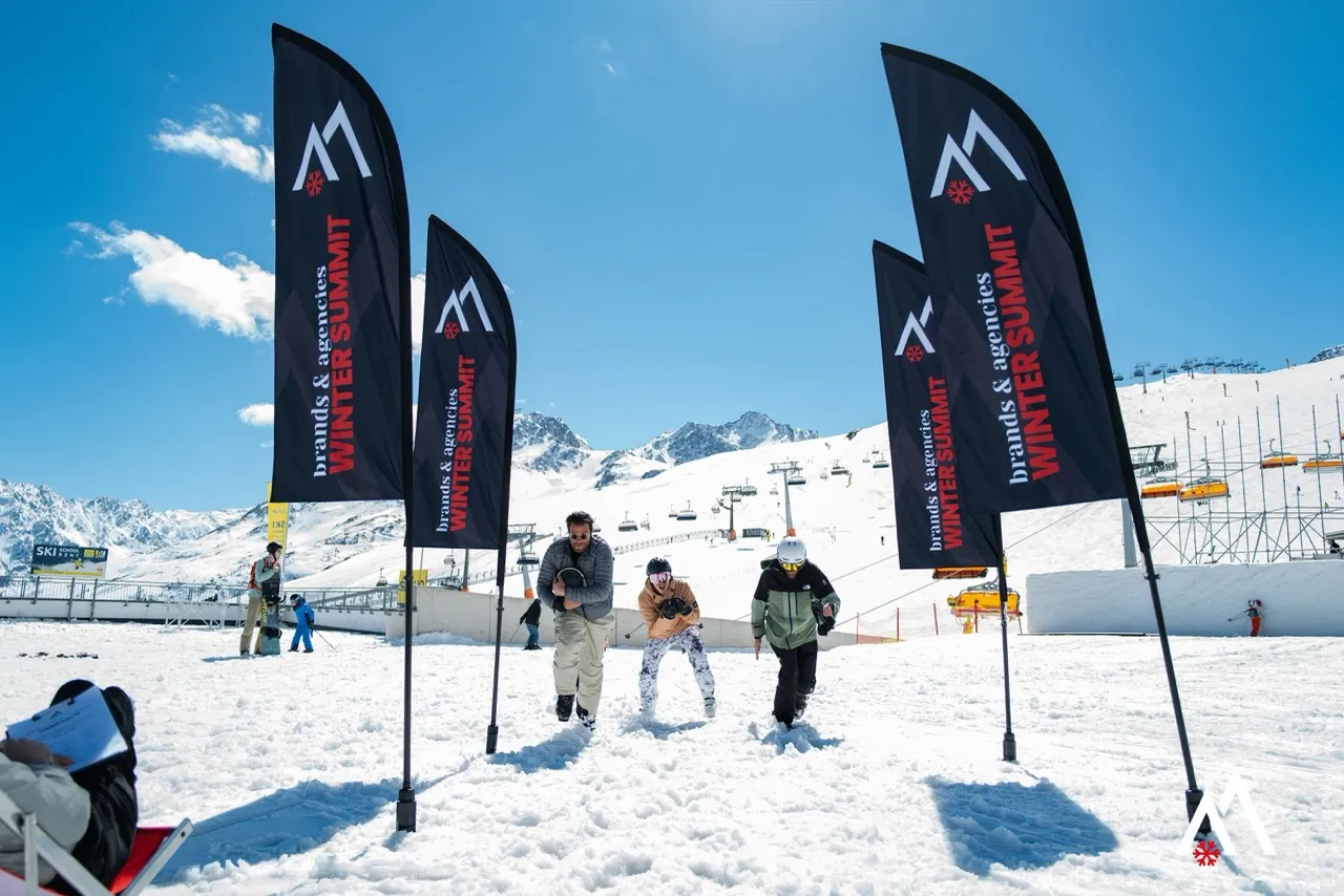 Teilnehmende laufen im Schnee zwischen den Beachflags des Brands & Agencies WINTER SUMMIT