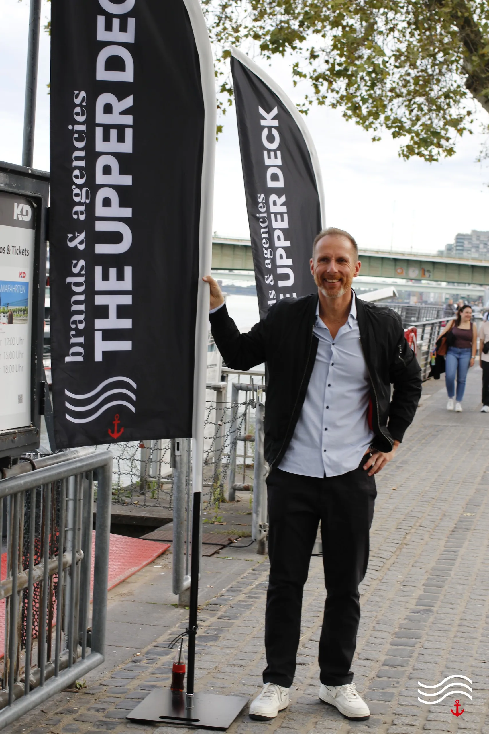 Gast bei der Ankunft am Rheinufer neben den THE UPPER DECK Beachflags – brands & agencies THE UPPER DECK 2026 in Köln
