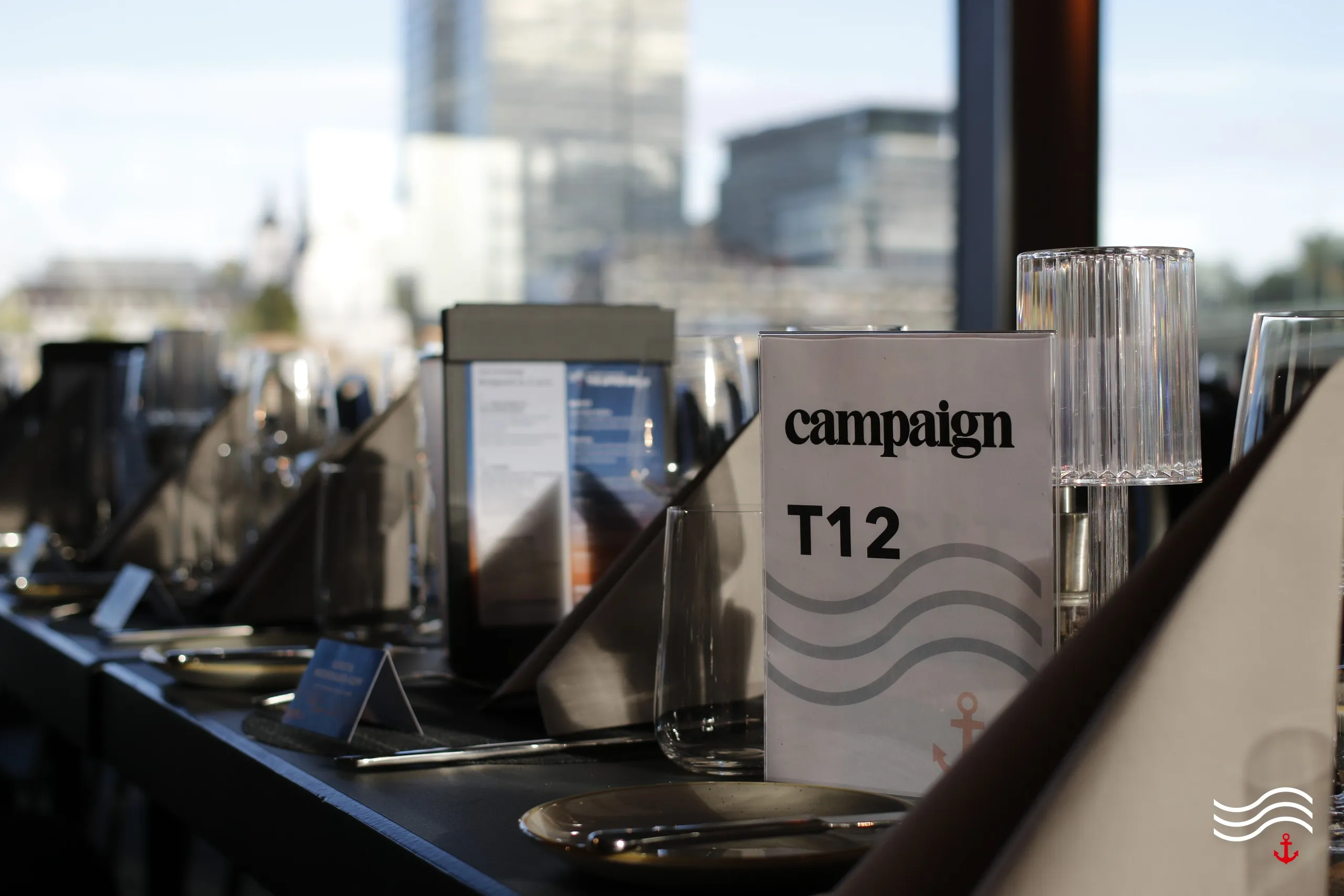 Eingedeckter Tisch mit Tischkarte von Campaign vor der Kölner Skyline – brands & agencies THE UPPER DECK 2026 in Köln