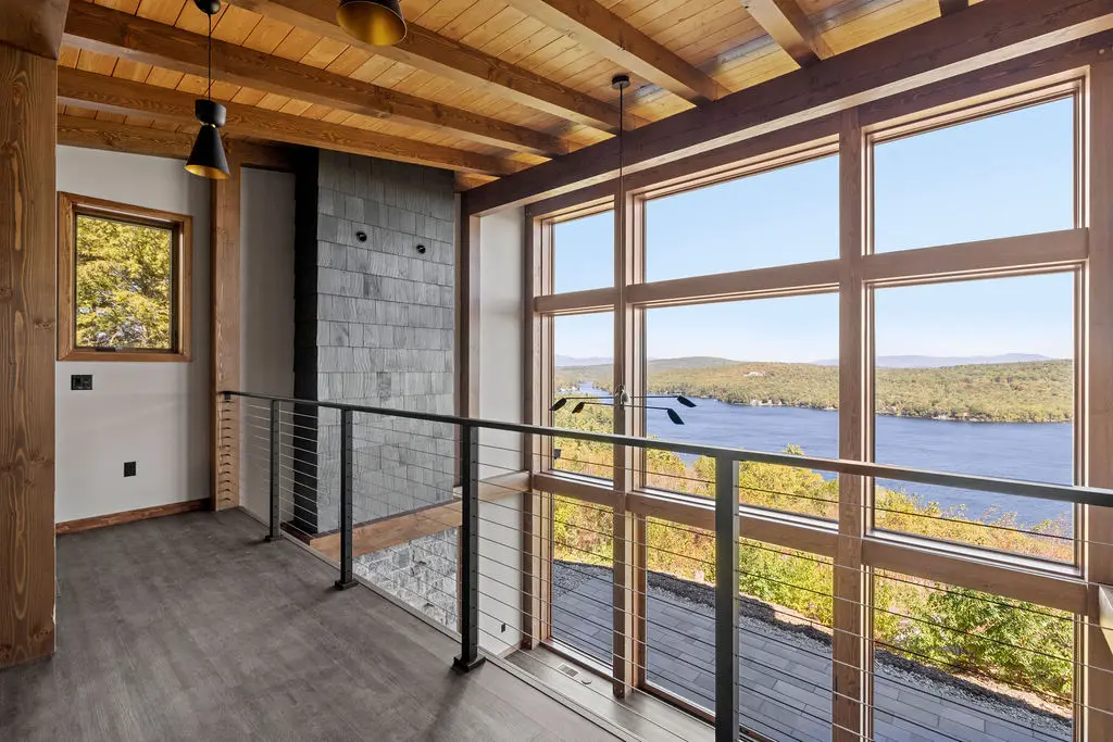 A custom timber frame lake house with large window walls overlooking the water.