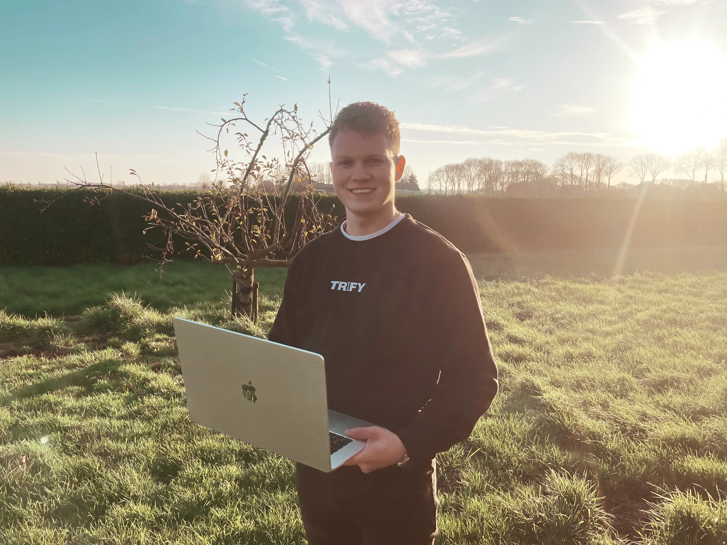 Robin Lindhout eigenaar van Trify lachend op foto met laptop in handen