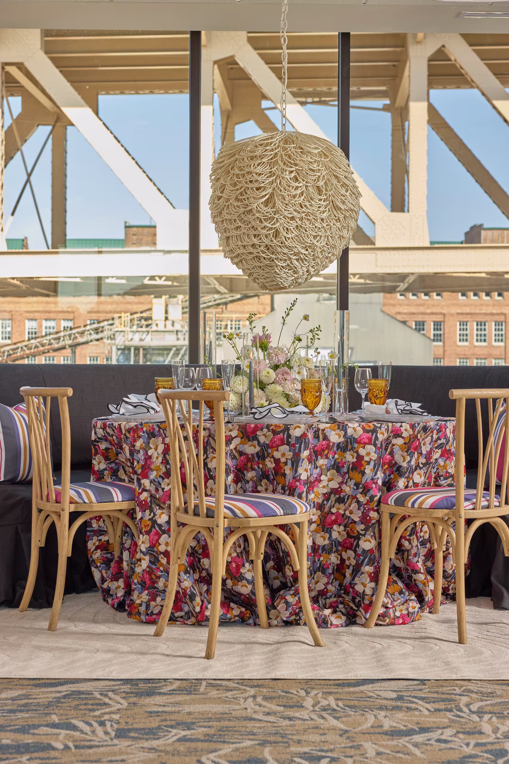 A comfortable and bohemian dining area, featuring a long purple couch, accented by a floral clothed table and neutral chairs. Photo by Adam Milliron