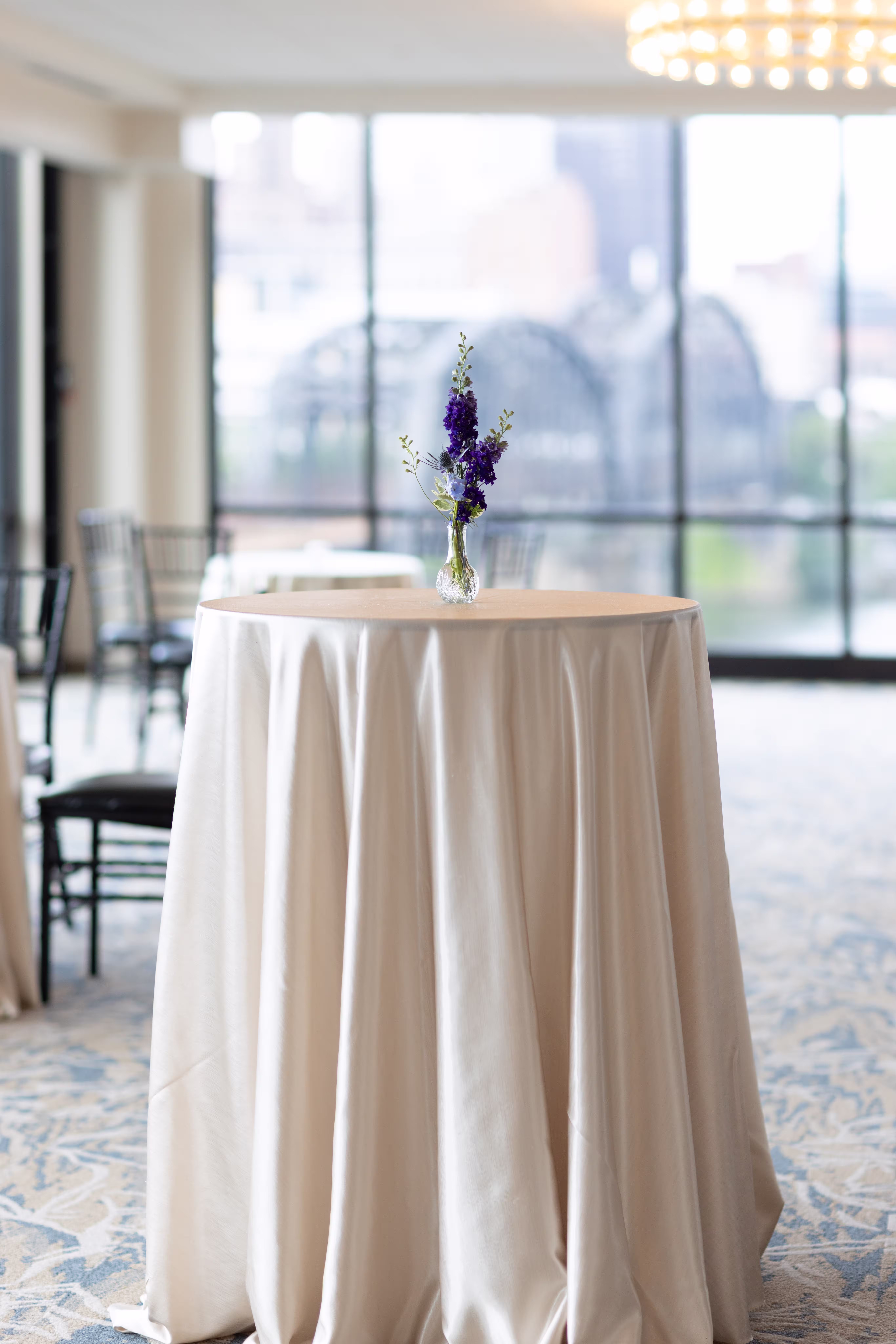 An isolated view of a simple and elegant cocktail hour table with a small vase of lavender at the center. Photo by Alex Mowery