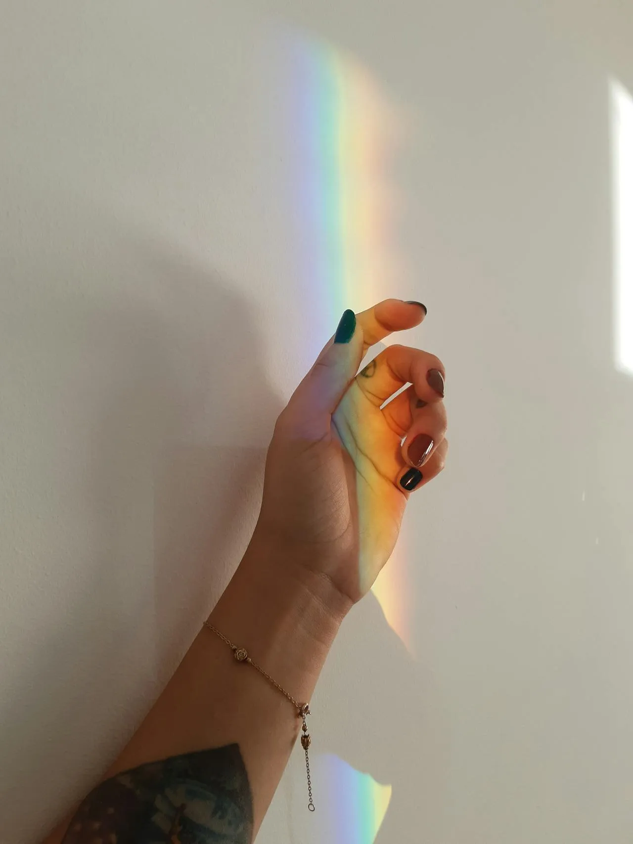 A woman's hand with a rainbow reflex on it.