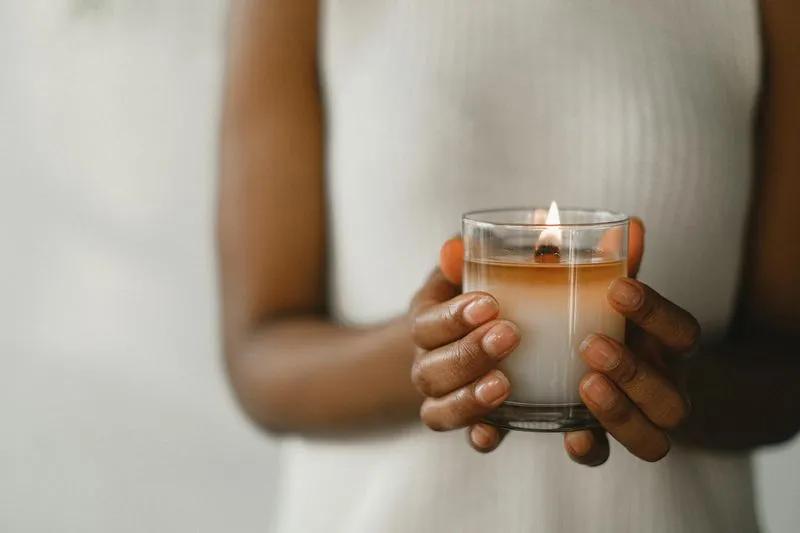 A woman holding a lit candle in her hands.