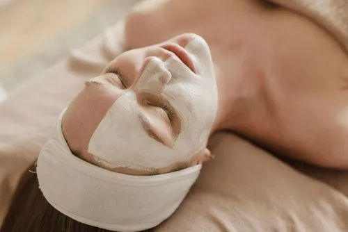 A woman laying on a bed with a facial mask on her face.