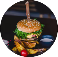 Burger with fried fries on black plate with sauce on the side