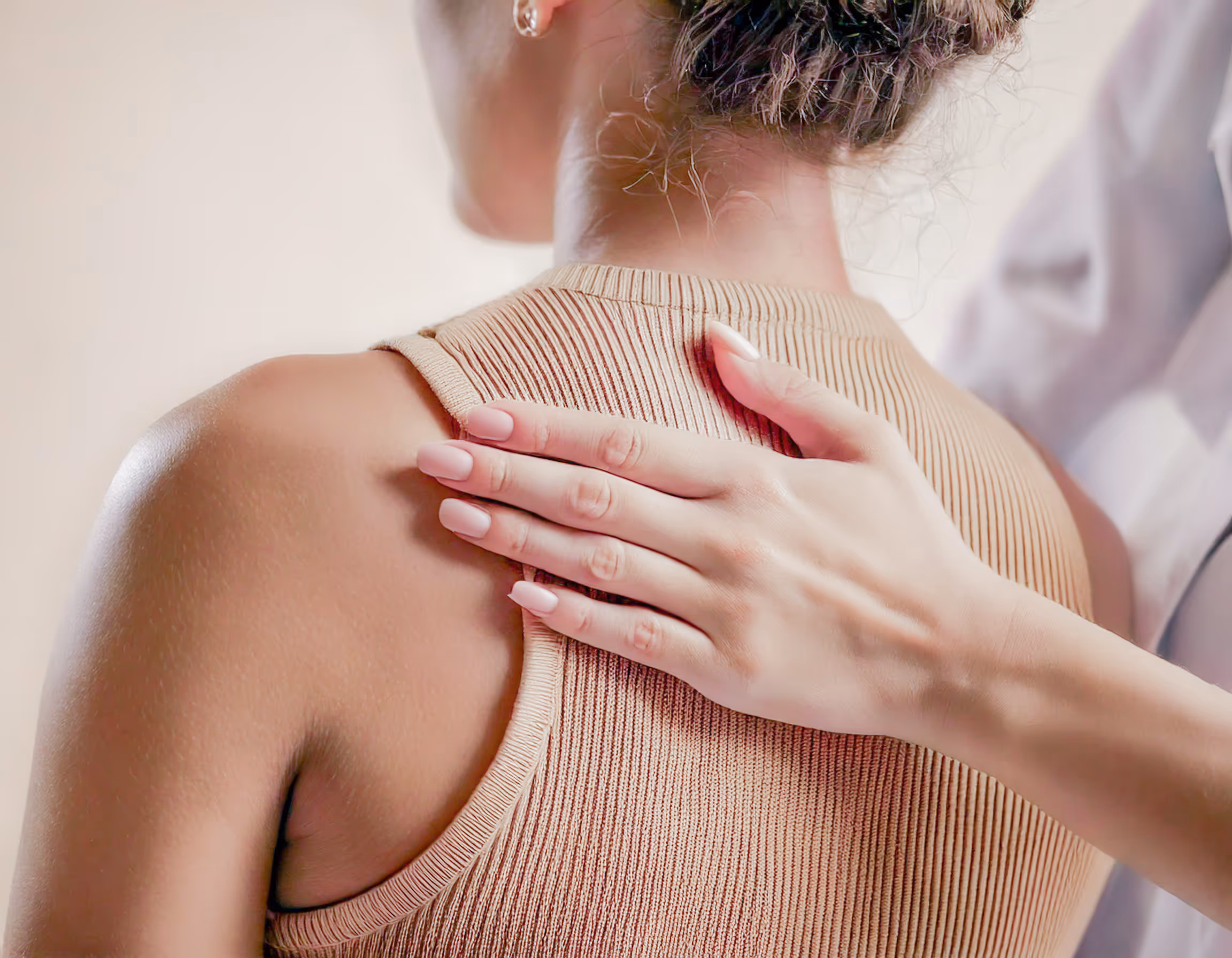 Physiotherapeutin behandelt Schulter einer Patientin im Sitzen
