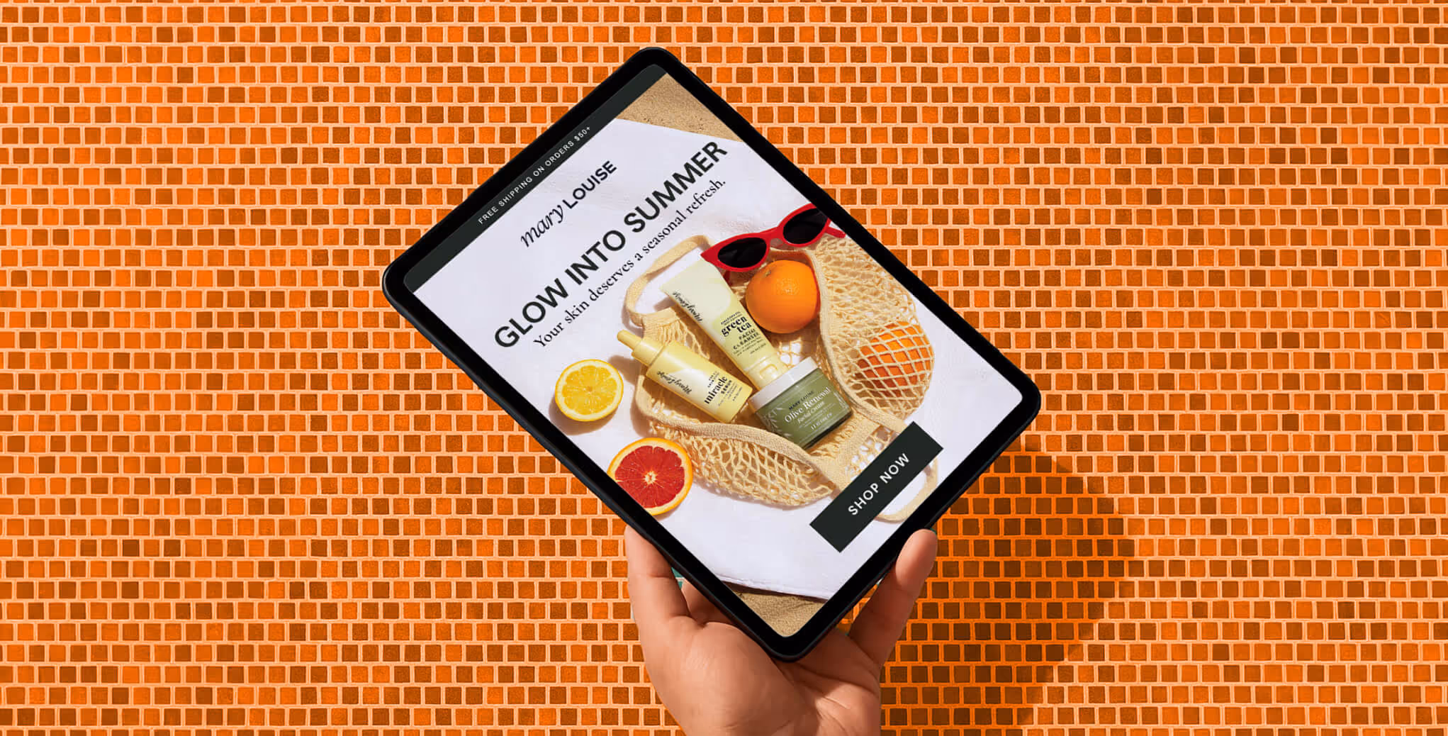 A hand holds a tablet showing Mary Louise skincare products with text “Glow Into Summer” on an orange tiled background.