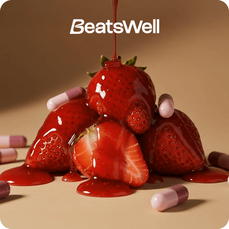Strawberries covered in glossy red syrup surrounded by pink capsules on a neutral background, representing BeatsWell wellness supplements.