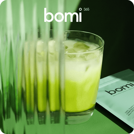 Green wellness drink in a glass with blurred vertical elements and Bomi 365 branding, styled as a modern health beverage product shot.