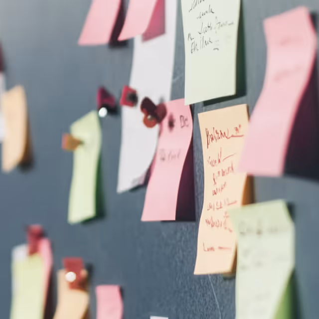 A collection of colorful sticky notes pinned to a dark wall, with handwritten notes and ideas scattered across them.