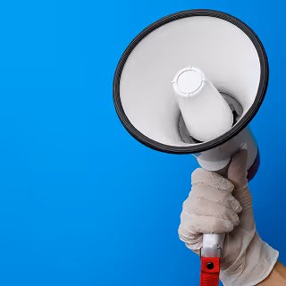 A hand wearing a white glove holds up a white and red megaphone against a bright blue background, symbolizing promotion or public announcement.