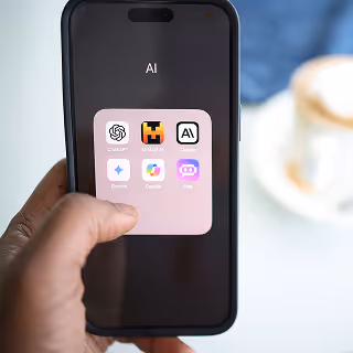 Close-up of a smartphone screen showing a folder labeled “AI” with icons for various AI apps, emphasizing mobile accessibility of AI tools.